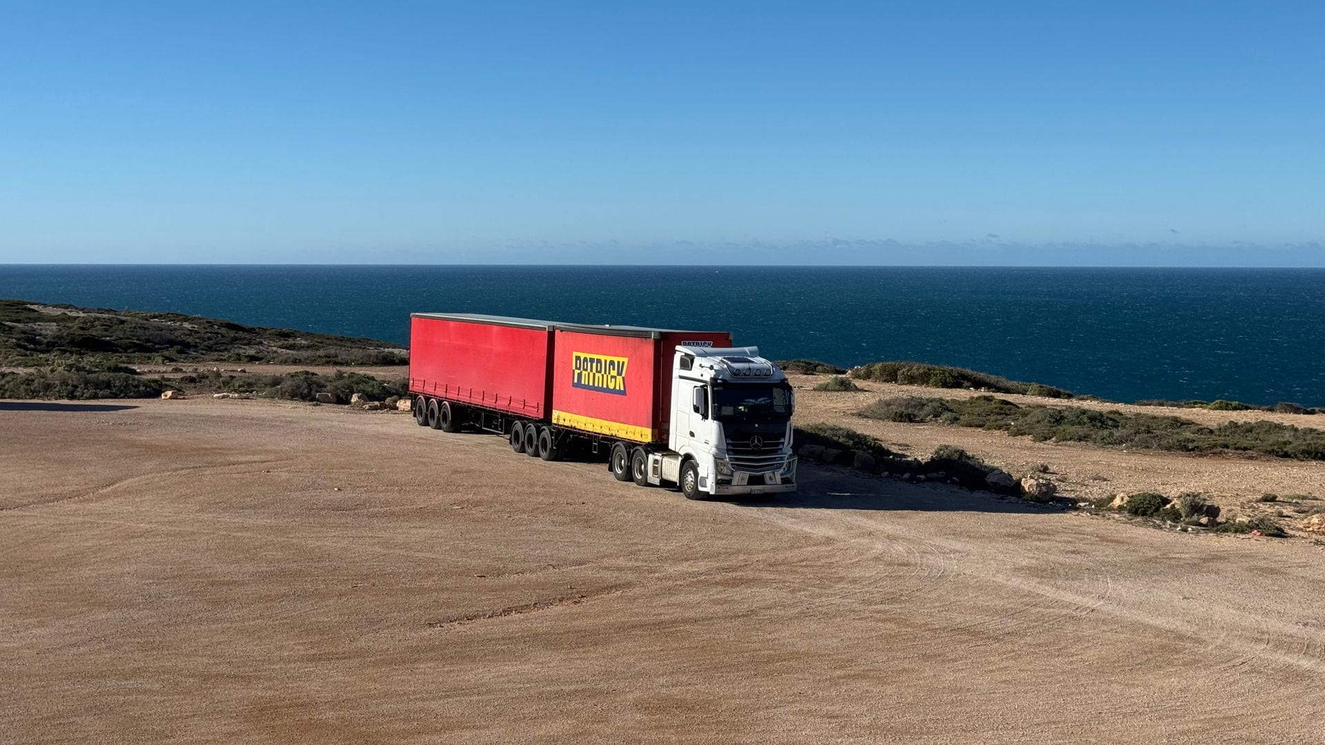 A curtainsider B-double parked on a coastal headland