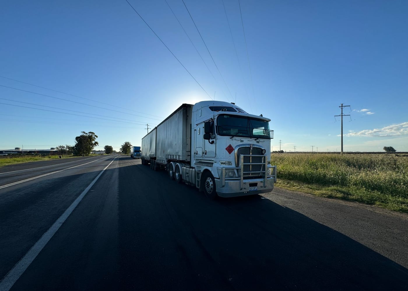A cab-over B-double on a highway at dusk