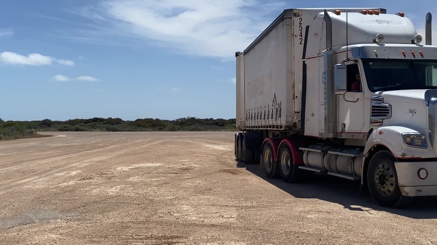 A road-stained prime mover and curtainsider on a gravel pad